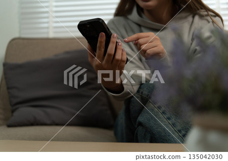 Cheerful woman use smartphone, enjoy personal chat exchanges messages through mobile application, learn new AI platform for business or fun, distracted from workflow on laptop in workplace. 135042030