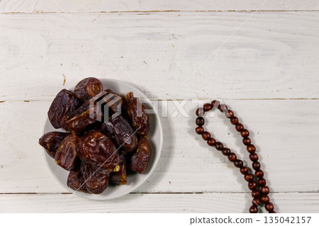 Dates fruit and rosary on white wooden table. Top view Dates fruit and rosary on white wooden table. Top view 135042157