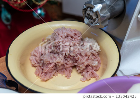 Ground Meat in Bowl From Electric Meat Grinder During Christmas Kitchen Prep 135042423