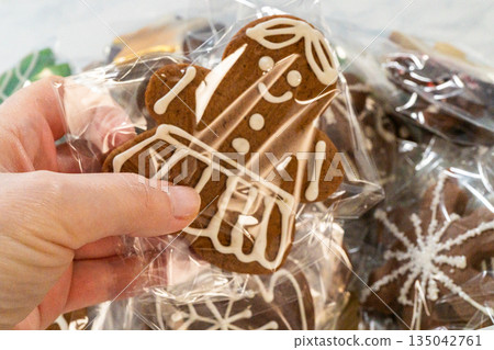 A collection of intricately decorated gingerbread cookies packaged in clear bags. The festive designs include snowflakes, mittens, and crowns piped in white icing, making them ideal for holiday gifts 135042761