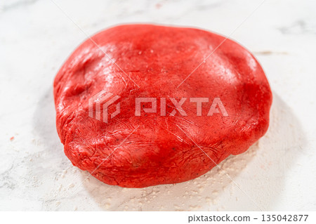 Freshly kneaded Red Gingerbread Cookies dough on a marble surface, vibrant red and ready for rolling. 135042877
