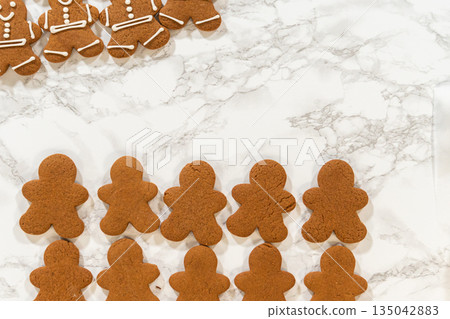 A close-up of fully decorated gingerbread man cookies, emphasizing the detailed icing patterns that make these festive treats stand out. 135042883