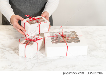 Two holiday cookie gift boxes, one large and one small, wrapped with red ribbon. The white boxes feature a clear window displaying beautifully decorated Christmas cookies, making them perfect for 135042902