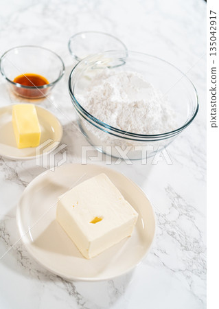 On the kitchen counter, the measured ingredients for the cream cheese frosting recipe await, promising a delightful and luscious treat. On the kitchen counter, the measured ingredients for the cream cheese frosting recipe await, promising a delightful and luscious treat. 135042917