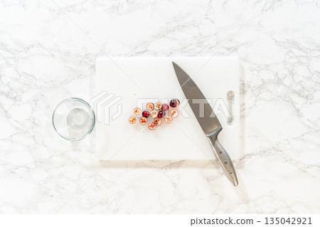 This image shows fresh cranberries being chopped on a cutting board, ready to be added to the cranberry buttercream for Lemon Spritz Cookies. 135042921