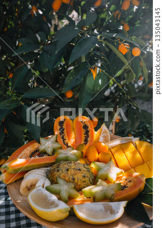 Colorful tropical fruit platter enjoyed in a garden setting on a sunny day 135043145