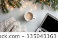 a cozy winter desk with coffee, knitted blanket, laptop, and festive lights in a minimalist flat lay 135043163