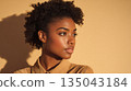 An elegant portrait of a confident woman with natural curly hair illuminated by warm minimal studio light 135043184