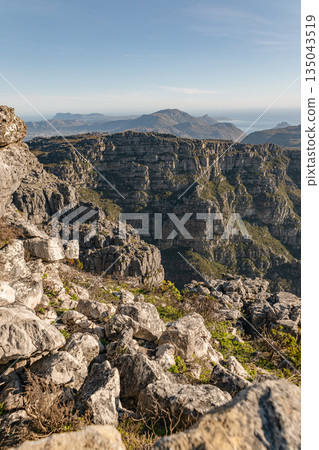 Scenic landscape of mountainous terrain with rocky cliffs and distant ocean Scenic landscape of mountainous terrain with rocky cliffs and distant ocean 135043519