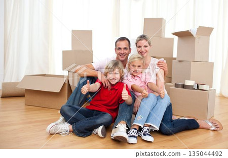 Cheerful family relaxing sitting on the floor Cheerful family relaxing sitting on the floor 135044492