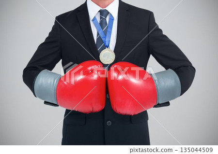 Midsection of businessman wearing red boxing gloves Midsection of businessman wearing red boxing gloves 135044509