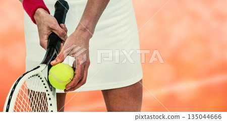 Midsection of sportswoman holding tennis racket Midsection of sportswoman holding tennis racket 135044666