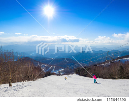 A view of the ungroomed snow course overlooking the mountains from a high vantage point at a ski resort in winter, with the sun shining brightly (Kawaba, Gunma Prefecture) 135044890