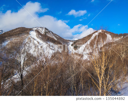 Snow-capped mountains and steep slopes stretching from two peaks seen from the middle of a winter ski resort (Kawaba, Gunma Prefecture) Snow-capped mountains and steep slopes stretching from two peaks seen from the middle of a winter ski resort (Kawaba, Gunma Prefecture) 135044892