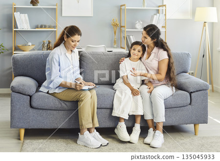 Child therapy session at home with counselor, mother offering support on sofa Child therapy session at home with counselor, mother offering support on sofa 135045933