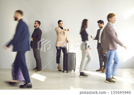 Woman waiting at the train station or airport among a blurred crowd of walking people Woman waiting at the train station or airport among a blurred crowd of walking people 135045940