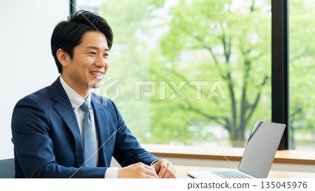 A young Japanese male employee smiling during a business meeting: A businessman with an impressive refreshing smile 135045976