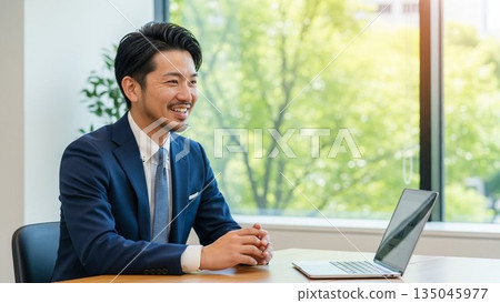 A young Japanese male employee smiling during a business meeting: A businessman with an impressive refreshing smile 135045977