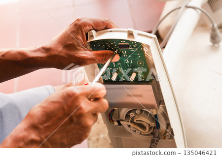 Close up of man repairing motherboard with screwdriver. 135046421