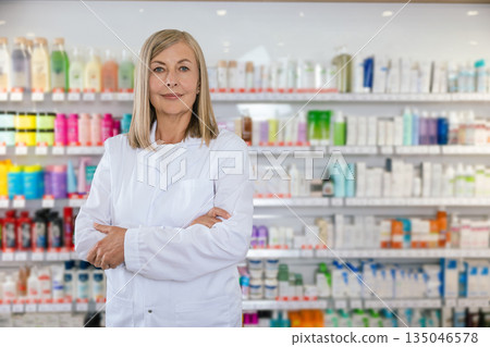 Positive and smiling mature woman in lab coat at the pharmacy Positive and smiling mature woman in lab coat at the pharmacy 135046578
