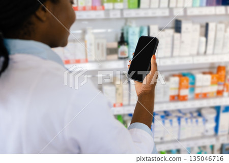 African american young woman in a lab coat holding a phone in her hands 135046716
