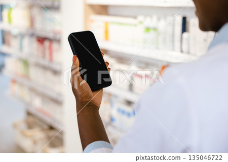 African american young woman in a lab coat holding a phone in her hands 135046722