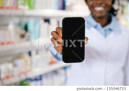 African american young woman in a lab coat holding a phone in her hands African american young woman in a lab coat holding a phone in her hands 135046725
