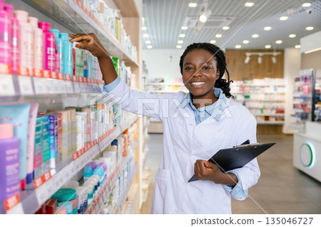 Young smiling pharmacist doing inventarization at the pharmacy Young smiling pharmacist doing inventarization at the pharmacy 135046727