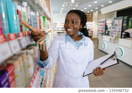 Young smiling pharmacist doing inventarization at the pharmacy Young smiling pharmacist doing inventarization at the pharmacy 135046732