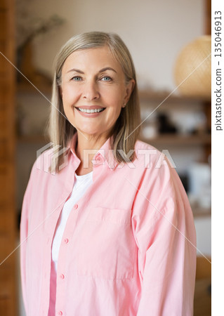 Mature woman standing in kitchen area with friendly smile 135046913