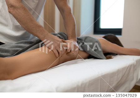 Doctor doing anti-cellulite massage to a woman lying on a couch Doctor doing anti-cellulite massage to a woman lying on a couch 135047029