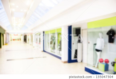 Mannequin wearing sports shirt black shorts in mall window under skylight showing sports balls 135047304