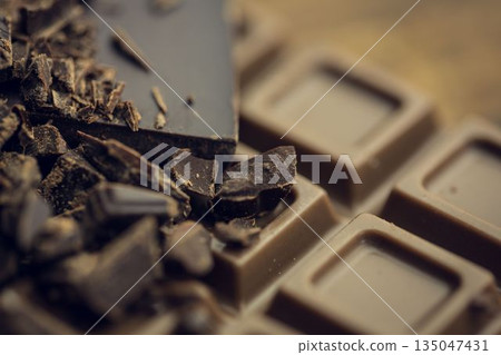 3D render is showing broken dark chocolate chunks resting atop milk chocolate bar with shallow blur 3D render is showing broken dark chocolate chunks resting atop milk chocolate bar with shallow blur 135047431