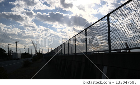 Chainlink fence silhouette and clear sky Chainlink fence silhouette and clear sky 135047595
