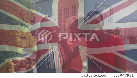 Standing family smiling while holding child's hands in front yard of home, wearing summer clothes Standing family smiling while holding child's hands in front yard of home, wearing summer clothes 135047951