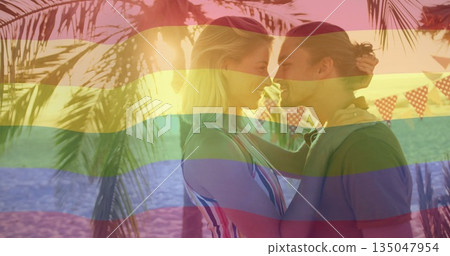 Leaning couple sharing intimate moment on tropical beach, with bunting flags overhead, copy space 135047954