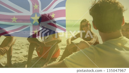 Chatting and smiling friends sitting on sandy beach near water's edge, with Niue flag overlay Chatting and smiling friends sitting on sandy beach near water's edge, with Niue flag overlay 135047967