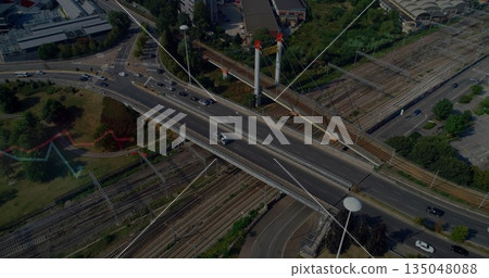 Spanning suspension bridge with pylons carrying cars above railway tracks at urban transit junction 135048088