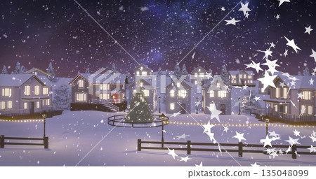 Glowing Christmas tree standing in village plaza at night with railing, string lights and lampposts 135048099