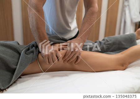 Doctor doing anti-cellulite massage to a woman lying on a couch Doctor doing anti-cellulite massage to a woman lying on a couch 135048375