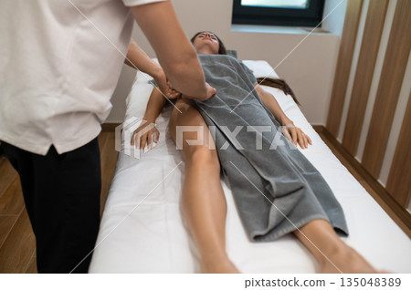 Woman lying on a couch at the manual therapist office and having massage session 135048389