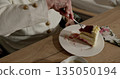 Older woman savoring delicious layered cake. Close-up shot of hand holding fork. Creamy dessert with berry topping on plate. Cozy and relaxed atmosphere. 135050194