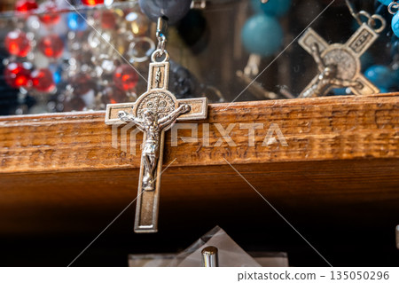 Different Christian crosses made of metal and wood hang for sale in a church store, symbolising faith, spirituality, religion, tradition, and sacred items. Religious symbol 135050296