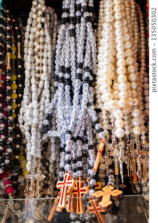 Different Christian crosses made of metal and wood hang for sale in a church store, symbolising faith, spirituality, religion, tradition, and sacred items. Religious symbol 135050302