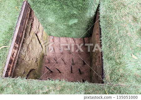 Vietnam War military pit trap with metal spikes hidden under grass cover historical Viet Cong defensive trap and guerrilla warfare concept 135051000