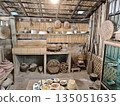 Rustic vintage kitchen room featuring bamboo wall and traditional wooden shelf with earthenware pottery and woven basket showing simple rural lifestyle and cultural nostalgia inside asian home 135051635