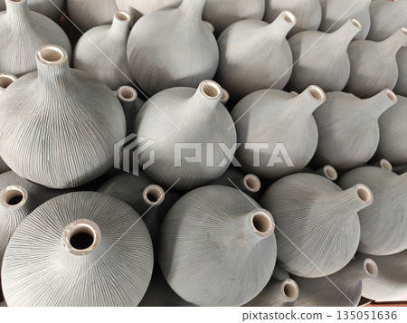 Large group of unglazed ceramic vase objects displayed in orderly pattern showing artistic texture and traditional craft design creating satisfying feeling of repetition and handmade beauty Large group of unglazed ceramic vase objects displayed in orderly pattern showing artistic texture and traditional craft design creating satisfying feeling of repetition and handmade beauty 135051636