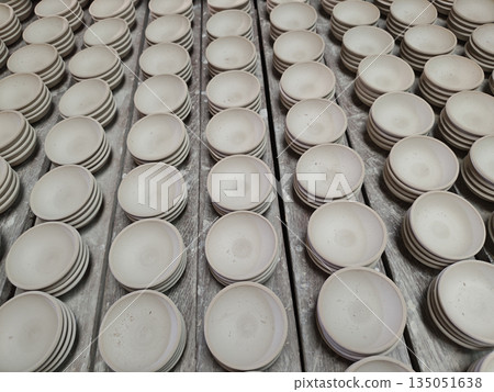 Rows of handmade ceramic bowl arranged neatly on wooden shelf drying in traditional pottery workshop creating satisfying pattern and feeling of calm productivity Rows of handmade ceramic bowl arranged neatly on wooden shelf drying in traditional pottery workshop creating satisfying pattern and feeling of calm productivity 135051638