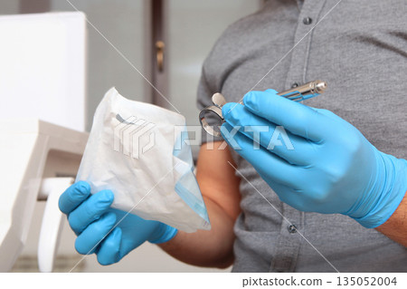 The doctor opens an airtight bag with a syringe for anesthesia. Dental syringe for anesthesia. The concept of modern medicine. Close-up. The doctor opens an airtight bag with a syringe for anesthesia. Dental syringe for anesthesia. The concept of modern medicine. Close-up. 135052004