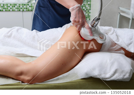 Anti-cellulite massage with ultrasound machine close-up. Hardware rejuvenation of the body. The procedure of RF lifting of the leg surface. The concept of maintaining skin tone and youth. 135052018